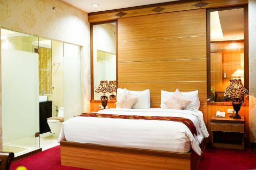 a bedroom with a large bed with a wooden headboard at Grand Buana Lestari Hotel in Duku