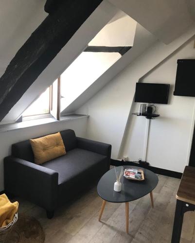 a living room with a black couch and a table at Honfleur : Appartement de charme. in Honfleur