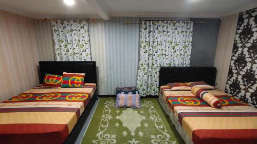 two beds sitting in a room with curtains at Anugerah Homestay Playen in Siyonokulon