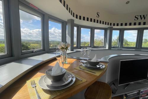 The Windmill Blackthorn Hill في بيسستر: غرفة طعام مع طاولة مع نظارة وتلفزيون