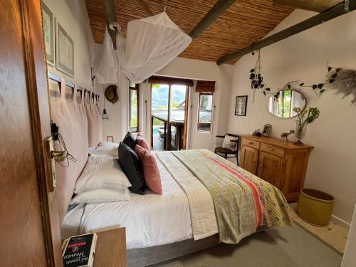 a bedroom with a bed with white sheets and a window at Treetops Cottage in Cape Town