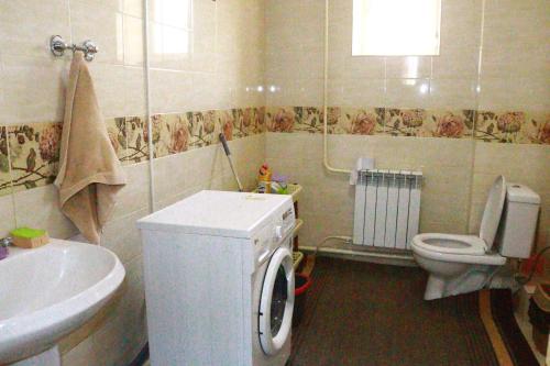 ein Badezimmer mit einem WC, einem Waschbecken und einer Waschmaschine in der Unterkunft Almaz Guesthouse Naryn in Orto-Saz