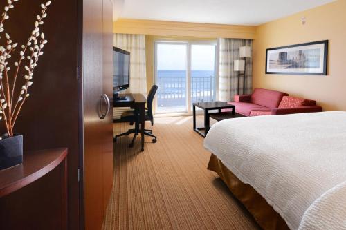 a hotel room with a bed and a living room at Courtyard by Marriott Galveston Island in Galveston