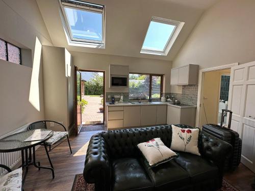 a living room with a black leather couch and a kitchen at Oranhill Lodge Guesthouse in Oranmore