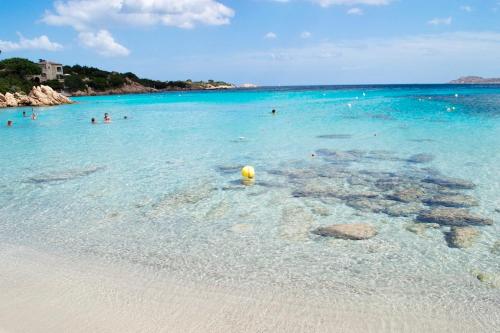 un grupo de personas en el agua en una playa en ISA-Residence in Marinella at only 450 m from the beach, apartments with air conditioning, en Marinella