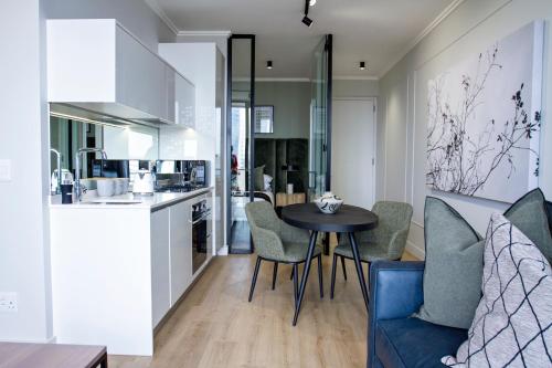eine Küche und ein Wohnzimmer mit einem Tisch und Stühlen in der Unterkunft Executive Apartment at Ellipse Waterfall in Midrand