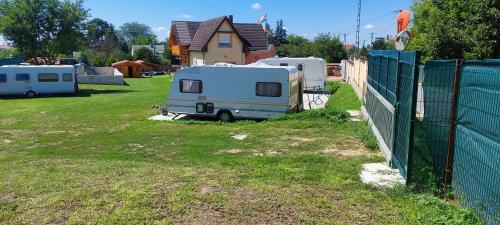 a group of rvs parked in a yard next to a fence at GyenesCamping Wohnwagen Knaus 1 Rechts in Gyenesdiás