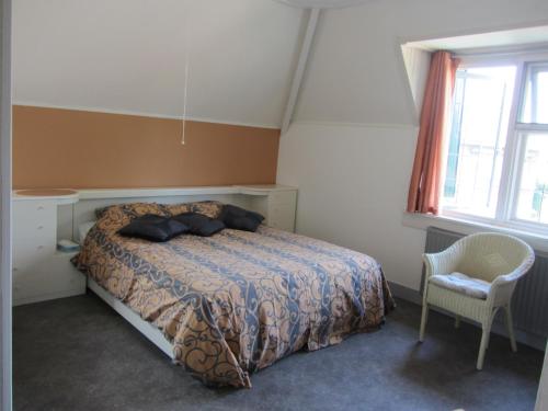 a bedroom with a bed and a chair and a window at de Flesch in Dodewaard