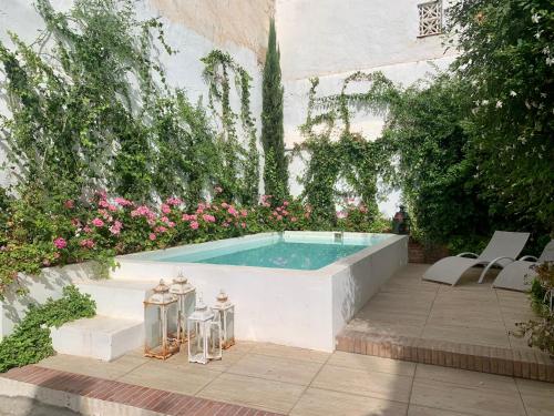 a swimming pool in a garden with pink flowers at Patios del Agua in El Puerto de Santa María