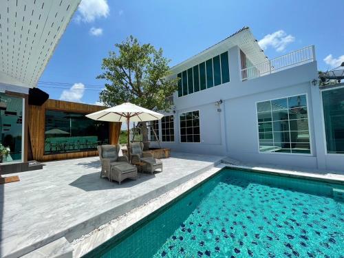 a swimming pool with two chairs and an umbrella next to a house at Skeyndor Health & Resort in Na Jomtien