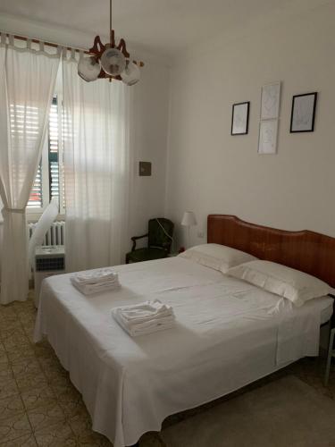 a bedroom with a bed with white sheets and a window at Clara Luna appartamento turistico in Osimo