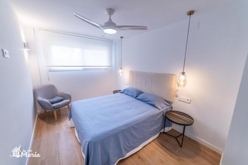 a bedroom with a bed and a chair and a window at La Iaia Maria in Gandía