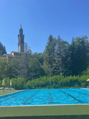 a large swimming pool with a clock tower in the background at B&B VillaDansio in Rezzoaglio