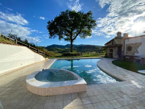 a swimming pool with a hot tub in front of a house at Villa Lucia - Homelike Villas in Camporotondo di Fiastrone