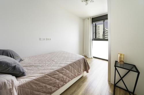 a white bedroom with a bed and a window at Sunsets and the pool in Barcelona in Cornellà de Llobregat