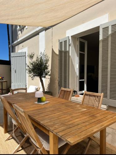 - une table en bois avec des chaises sur la terrasse dans l'établissement Casa Andréa Agreable T3 avec grand jardin à 3mn de la plage, à Sanary-sur-Mer