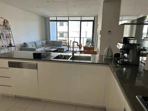 a kitchen with a sink and a living room at Private ensuite room in a beautiful nature area in Sydney