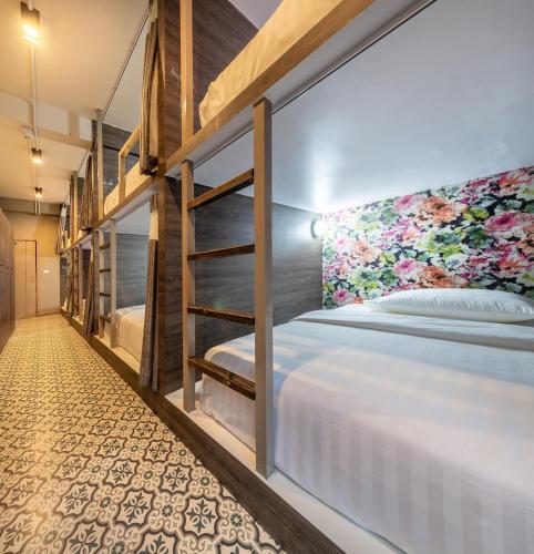 a bedroom with bunk beds with a floral wall at Happy Station Bangkok in Bangkok