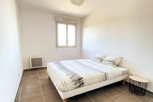 a white bedroom with a bed and a window at Esprit du Sud - Terrasse & Parking in Brignoles