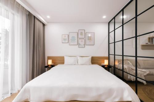 a bedroom with a large white bed and two lamps at LAGOM APARTMENT AND HOTEL in Da Nang