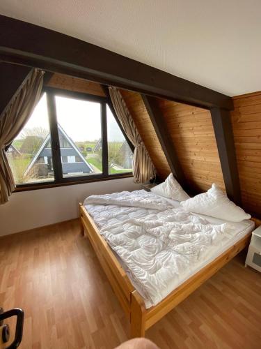 a large bed in a room with a large window at Ferienpark Fedderwardersiel in Fedderwarderdeich