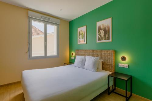 een slaapkamer met een wit bed en een groene muur bij Hôtel de la Tour in La Tour-du-Pin