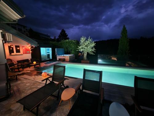 a patio with chairs and a swimming pool at night at Bella Flocon appartements min 2 Nights Special weekly and monthly prices in Savièse