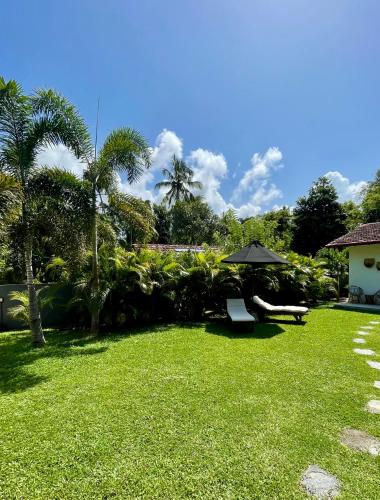 a lawn with an umbrella and a bench in a yard at Kanferri Villa in Ahangama