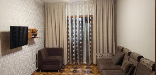 una sala de estar con un sofá y una silla en Yunusabad apartment 19, 1, en Magaldarkhan