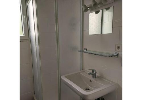 a white bathroom with a sink and a shower at Ferienpark Fedderwardersiel in Fedderwarderdeich