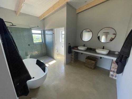 uma casa de banho com uma banheira grande, 2 lavatórios e uma banheira. em Windon vineyard farmhouse em Stellenbosch