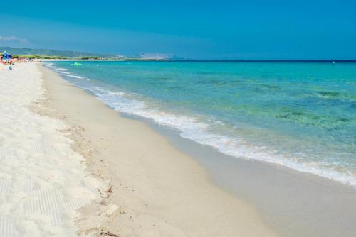 a sandy beach with the ocean and people on it at ISA-Apartments with air conditioning and external outdoor space in Budoni, at only 300 m from the beach in Budoni