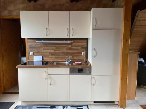 a kitchen with white cabinets and a sink at Ferienpark Fedderwardersiel in Fedderwarderdeich