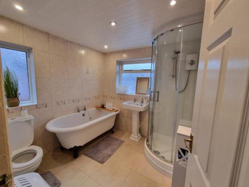 a bathroom with a tub and a toilet and a sink at Comfortable Business and Family Home in Manchester