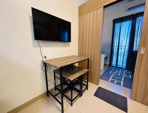 a room with a table and a television on a wall at Victoria’s Place in Manila