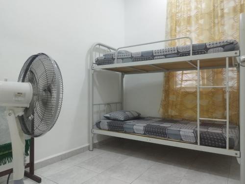 a room with two bunk beds and a fan at Bushra Guest House, Batu Pahat in Batu Pahat