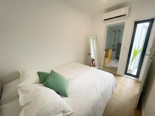 a white bed with a green pillow in a room at green guest house. Figueira da Foz in Figueira da Foz