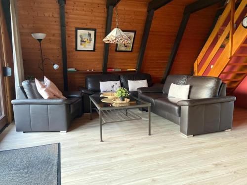 a living room with two leather couches and a table at Ferienpark Fedderwardersiel in Fedderwarderdeich