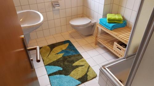 La salle de bains est pourvue d'un lavabo, de toilettes et d'un tapis. dans l'établissement Ferienhaus Anjofina Ferienwohnung Kobel, à Altenau