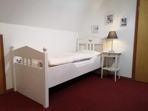- une chambre avec un lit blanc et une table de nuit dans l'établissement Ferienhaus Anjofina Ferienwohnung Kobel, à Altenau