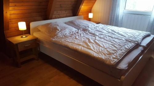 a bed in a bedroom with two lamps on tables at Ferienpark Fedderwardersiel in Fedderwarderdeich