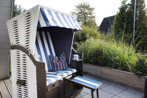 a bench with a blue and white awning on a patio at Ferienpark Fedderwardersiel in Fedderwarderdeich