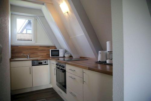 a kitchen with white cabinets and a window at Ferienpark Fedderwardersiel in Fedderwarderdeich