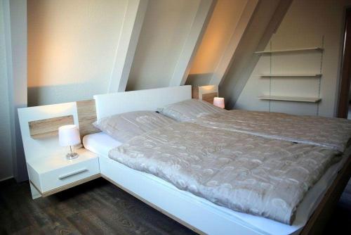a bedroom with a white bed with two lamps on it at Ferienpark Fedderwardersiel in Fedderwarderdeich