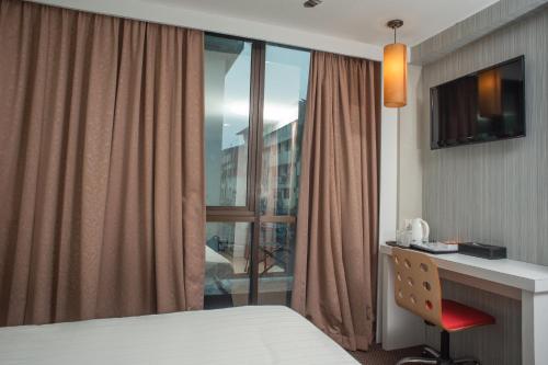 ビントゥルにあるCapital O 90083 Riverfront Innのベッド、デスク、窓が備わるホテルルームです。
