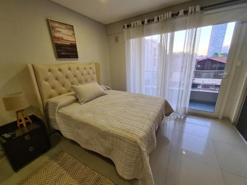 a bedroom with a bed and a large window at Moderno Monoambiente Amoblado en Equipetrol in Santa Cruz de la Sierra