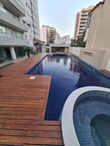 una piscina con terraza de madera y un edificio en Moderno Monoambiente Amoblado en Equipetrol, en Santa Cruz de la Sierra