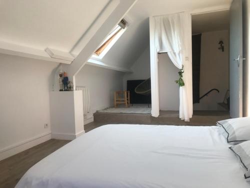 ein großes weißes Bett in einem Zimmer mit Fenster in der Unterkunft abri du marin in Séné