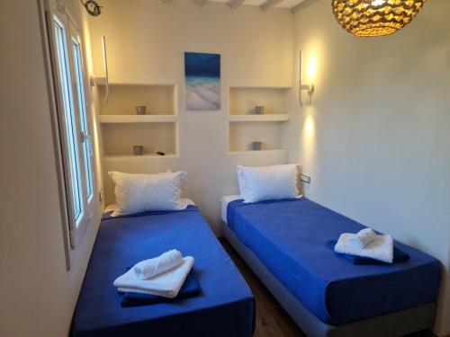 two beds in a room with towels on them at Empyreal Blue Apartments in Dexamenes