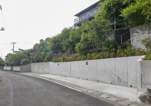 a concrete wall next to a road with a building at GLAMDAY PORT in Atami